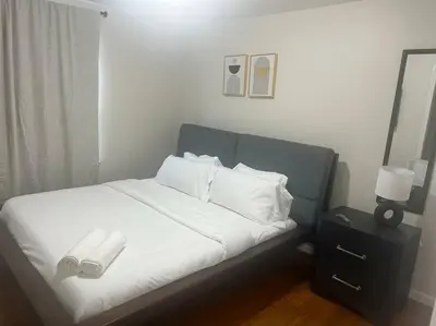 a bed with white sheets and pillows and a mirror at Exquisite 4 Beds Near EWR NYC in East Orange
