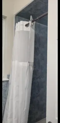 a white shower curtain hanging in a bathroom at Exquisite 4 Beds Near EWR NYC in East Orange