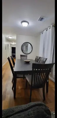 a black dining room table with chairs and a mirror at Exquisite 4 Beds Near EWR NYC in East Orange