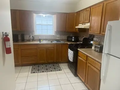 a kitchen with wooden cabinets and a sink and a refrigerator at Exquisite 4 Beds Near EWR NYC in East Orange