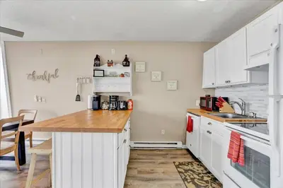 a kitchen with white cabinets and a wooden counter top at Pet Friendly! Lakefront w Hot Tub, Firepit! in Tobyhanna