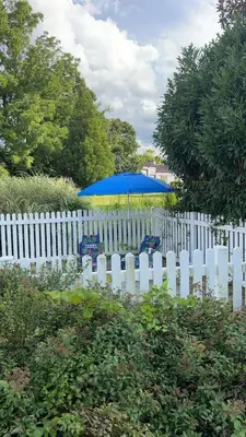 a white picket fence with a blue umbrella and a white picket fencestration at THE VILLA Farm Sleeps 20 more in Montgomery