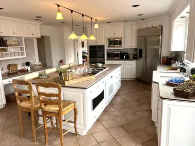 a kitchen with white cabinets and a kitchen island with chairs at THE VILLA Farm Sleeps 20 more in Montgomery