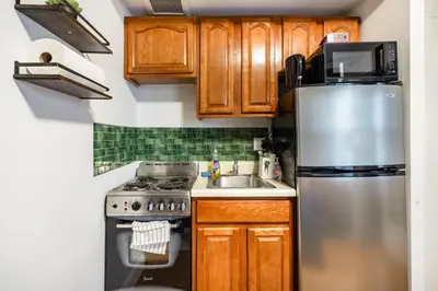 a kitchen with wooden cabinets and a stainless steel refrigerator at 2 Bedroom Home Unit In Lower Manhattan in New York