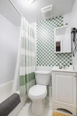 a bathroom with a toilet and a green and white shower curtain at 2 Bedroom Home Unit In Lower Manhattan in New York