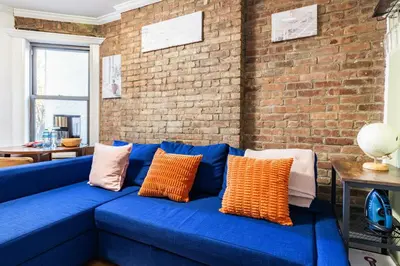 a blue couch in a room with a brick wall at 2 Bedroom Home Unit In Lower Manhattan in New York