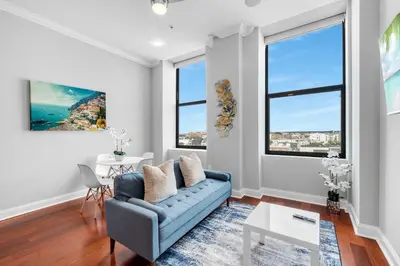 a living room with a blue couch and windows at Modern 1BR with Rooftop Pool & Gym in Philadelphia