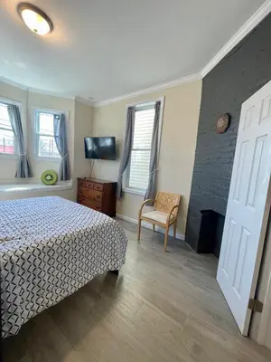 a bedroom with a bed and a chair and a fireplace at New York City Private Bedroom Near Free Ferry Boat! in Stapleton