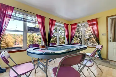 a room with a table and chairs and windows at Modern Lakefront Oasis Relaxing Hot Tub Sauna Game Rooms Stunning Views! in East Stroudsburg