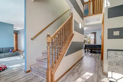 a staircase in a living room with wooden floors at Modern Lakefront Oasis Relaxing Hot Tub Sauna Game Rooms Stunning Views! in East Stroudsburg