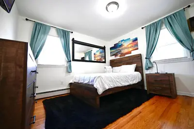 a bedroom with a bed with blue curtains and a mirror at Bright & cozy 2nd Floor Apartment Close to NYC in Bloomfield