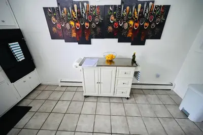 a kitchen with a small white cabinet and paintings on the wall at Bright & cozy 2nd Floor Apartment Close to NYC in Bloomfield