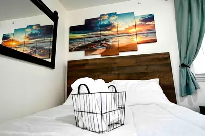 a bedroom with a white bed with four paintings on the wall at Bright & cozy 2nd Floor Apartment Close to NYC in Bloomfield