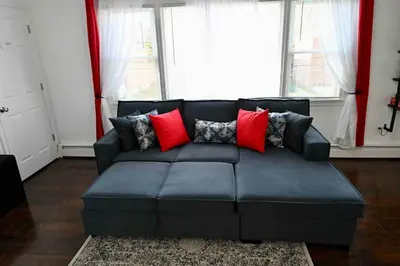 a living room with a blue couch with red pillows at Bright & cozy 2nd Floor Apartment Close to NYC in Bloomfield