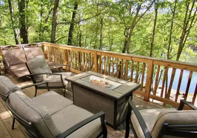 a deck with chairs and a table with a fire pit at Charming Lakefront Getaway with Hot Tub & Game Room Perfect for Families! in East Stroudsburg