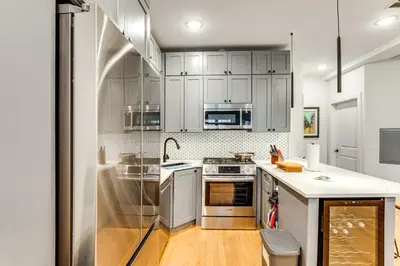 a kitchen with white cabinets and stainless steel appliances at Walk to Journal Square Modern Apt about 4 Mi to NYC! in Jersey City