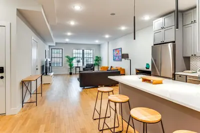 a kitchen and living room with a counter and stools at Walk to Journal Square Modern Apt about 4 Mi to NYC! in Jersey City