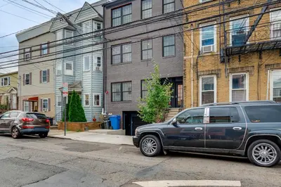 a black suv parked on a street in front of buildings at Walk to Journal Square Modern Apt about 4 Mi to NYC! in Jersey City
