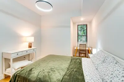 a white bedroom with a bed and a desk at Walk to Journal Square Modern Apt about 4 Mi to NYC! in Jersey City