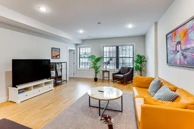a living room with a couch and a flat screen tv at Walk to Journal Square Modern Apt about 4 Mi to NYC! in Jersey City