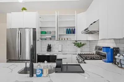 a kitchen with white cabinets and a stainless steel refrigerator at Skyline Serenity Luxe NYC Retreat in Jersey City