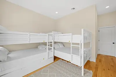 two white bunk beds in a room with wooden floors at Skyline Serenity Luxe NYC Retreat in Jersey City