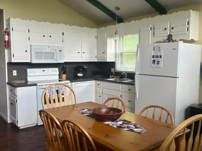 a kitchen with a wooden table and white appliances at Fenced Yard Chalets from Good Dog Vacations at Big Valley Resort in Sciota