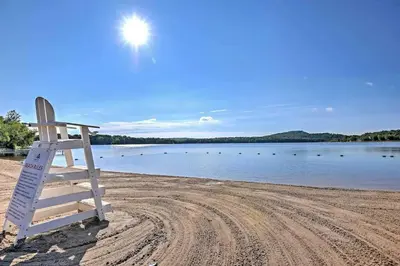 a lifeguard chair sitting on a beach near a body of water at Pocono Lake House Beach, AC in Locust Lakes Village