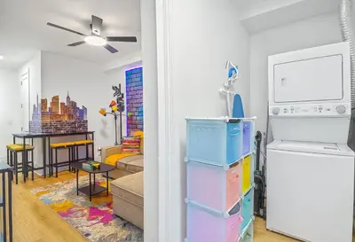 a living room with a refrigerator and a table at Hoboken Hideaway - Walk to Transit - 15 Mins to NYC in Hoboken