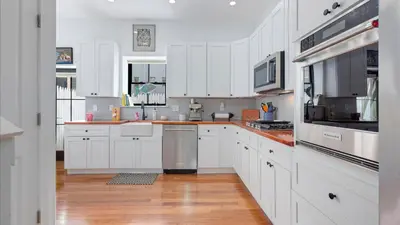 a white kitchen with wooden floors and white cabinets at Modern Chic Fishtown-Philly Home with Roof Deck in Philadelphia