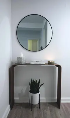 a mirror on a wall above a table with a potted plant at One Dutch Hotel in New York