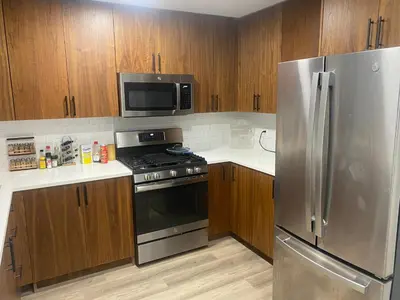 a kitchen with stainless steel appliances and wooden cabinets at Cozy apt with City skyline rooftop in Union City