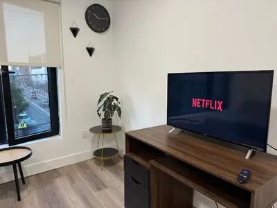 a flat screen tv sitting on top of a wooden entertainment center at Cozy apt with City skyline rooftop in Union City