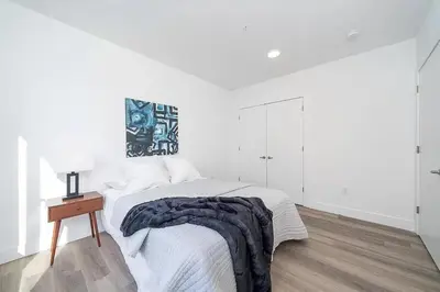 a white bedroom with a bed and a table at Cozy apt with City skyline rooftop in Union City