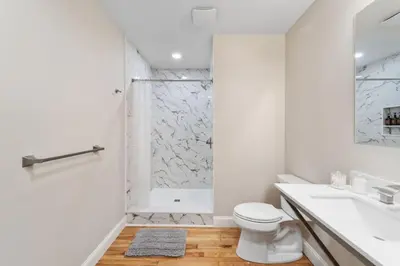 a white bathroom with a shower and a toilet at Hip Dtwn Apt With Arcade And Gym in Binghamton