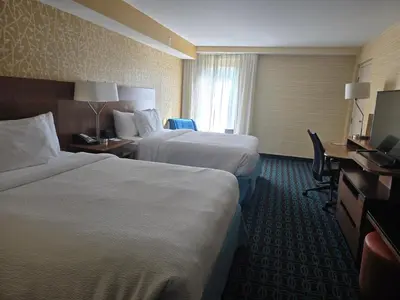 a hotel room with two beds and a desk at Fairfield by Marriott in Paramus