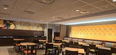 a restaurant with tables and chairs and a yellow wall at Fairfield by Marriott in Paramus