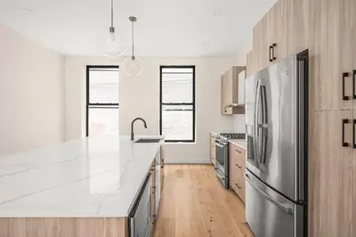 a kitchen with a stainless steel refrigerator and wooden cabinets at Harlington by Rove Travel Private Backyard & Roof in New York