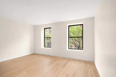 an empty white room with two windows and a wooden floor at Harlington by Rove Travel Private Backyard & Roof in New York
