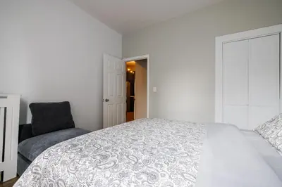 a white bedroom with a bed and a chair at Ultimate Urban living at Centrally Located Apartments in New York