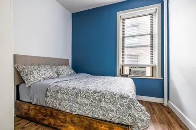 a bedroom with a bed with blue walls and a window at Ultimate Urban living at Centrally Located Apartments in New York