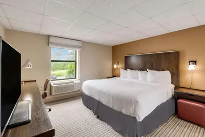 a hotel room with a bed and a flat screen tv at The Crossroads Hotel - Newburgh in Newburgh
