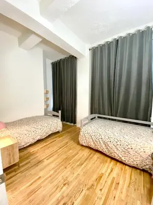 two beds in a room with wooden floors and curtains at GREAT APT 2 BED ROOM GREAT LOCATION nye in New York