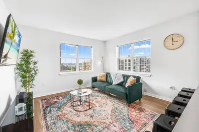 a living room with a green couch and a clock at Supreme 2 Bedroom Condo in Prime Jersey City in Jersey City