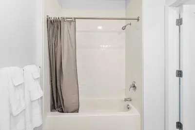 a white bathroom with a shower and a tub at Supreme 2 Bedroom Condo in Prime Jersey City in Jersey City