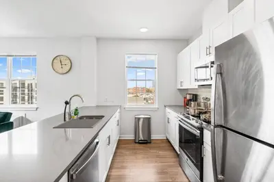 a kitchen with white cabinets and a stainless steel refrigerator at Supreme 2 Bedroom Condo in Prime Jersey City in Jersey City