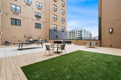 a patio with grass and tables and a building at Luxury Living in Jersey City Only Steps Away from Manhattan in Jersey City