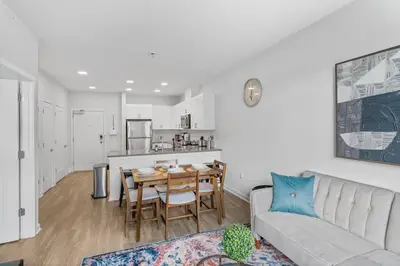 a living room with a couch and a table and a kitchen at Luxury Living in Jersey City Only Steps Away from Manhattan in Jersey City