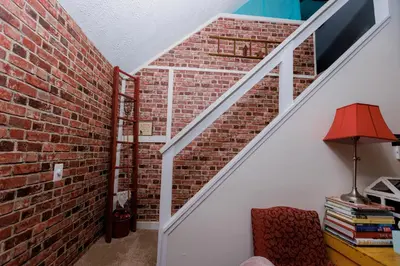 a room with a brick wall and a staircase at WOW!! Ultimate Pocono Retreat Hot Tub, Game Room, Fire Pit, Near Lakes & Hiking! in Blakeslee
