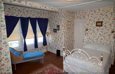 a bedroom with a white bed and floral wallpaper at The White House in Plainfield